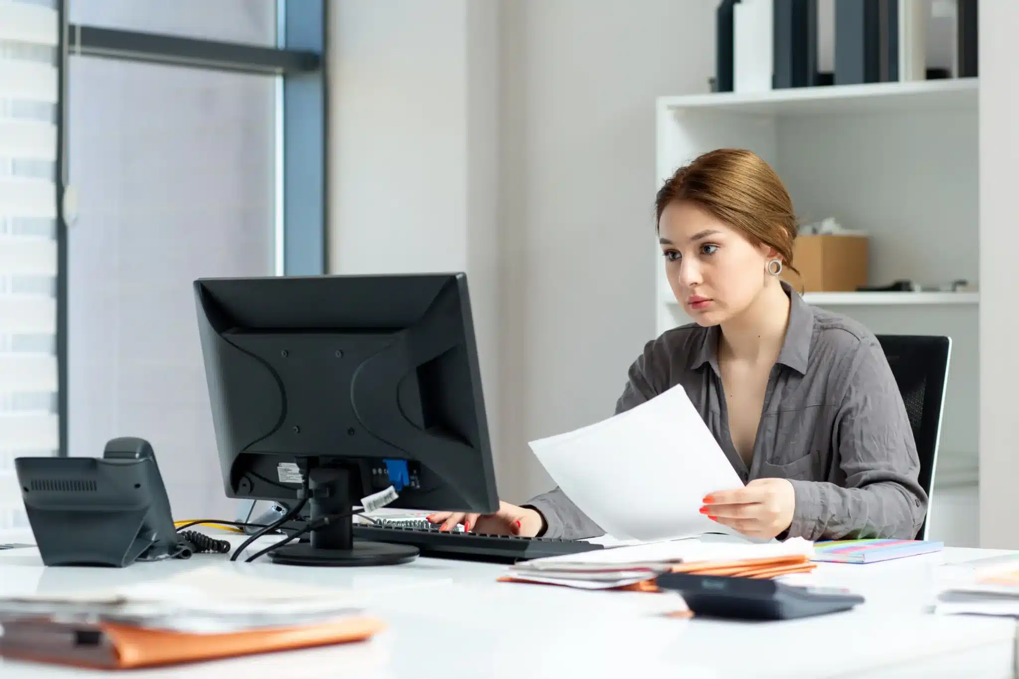 front view young beautiful lady grey shirt working her pc sitting inside her office daytime building job activity Web H scaled