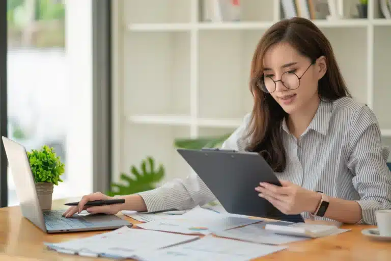 working-woman-looking-document-working-desk-with-laptop-computer-paperwork-concept